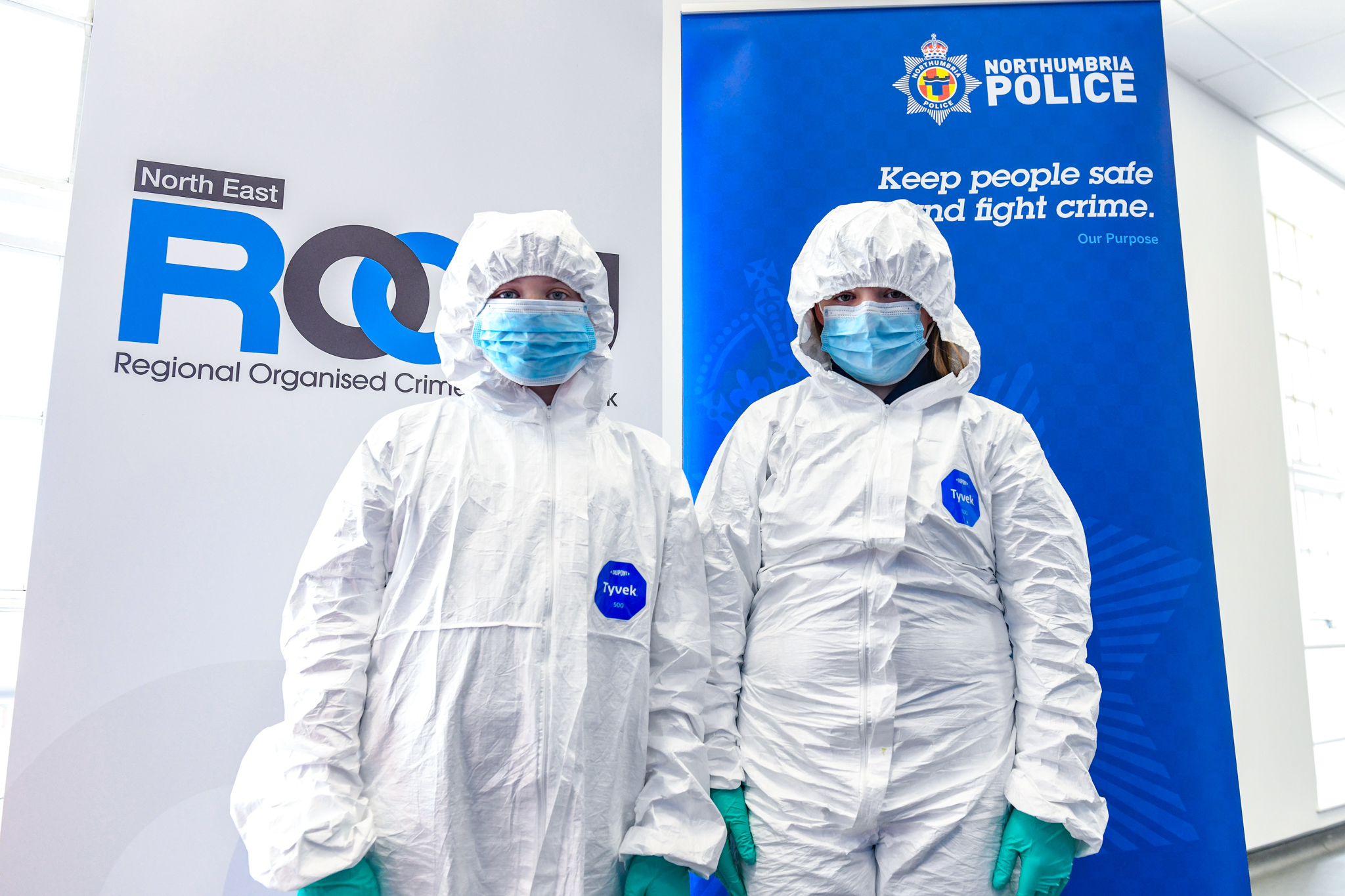 Two young students dressed in white crime scene suits, face masks and gloves.